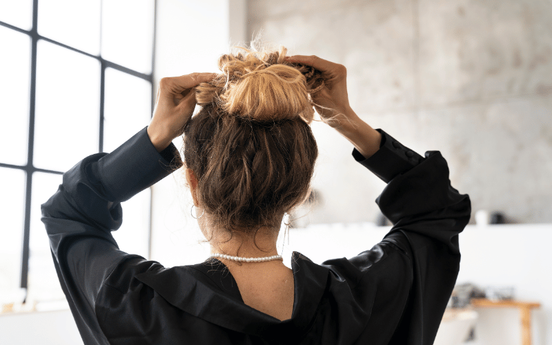 moça de costas fazendo coque no cabelo