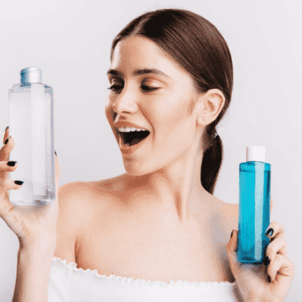 mulher olhando dois vidros de agua micelar em duvida de qual é a melhor agua micelar